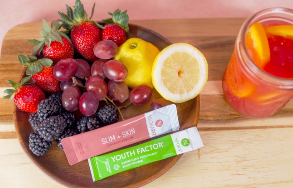 NeoraFit Slim + Glow Collagen Powder and Youth Factor Superfood & Antioxidant Boost Powder laying with a bowl of fruit and a drink